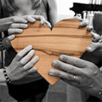 wooden heart in color with hands around it in black and white